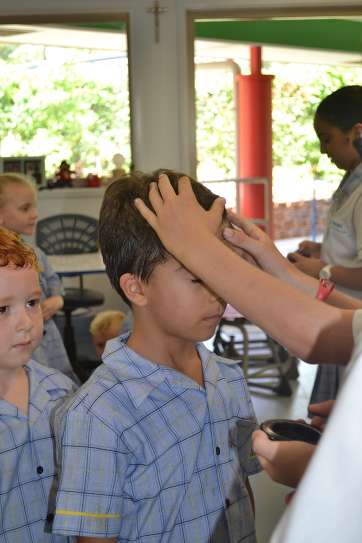 A student is receiving ash on the forehead for ash wednesday.