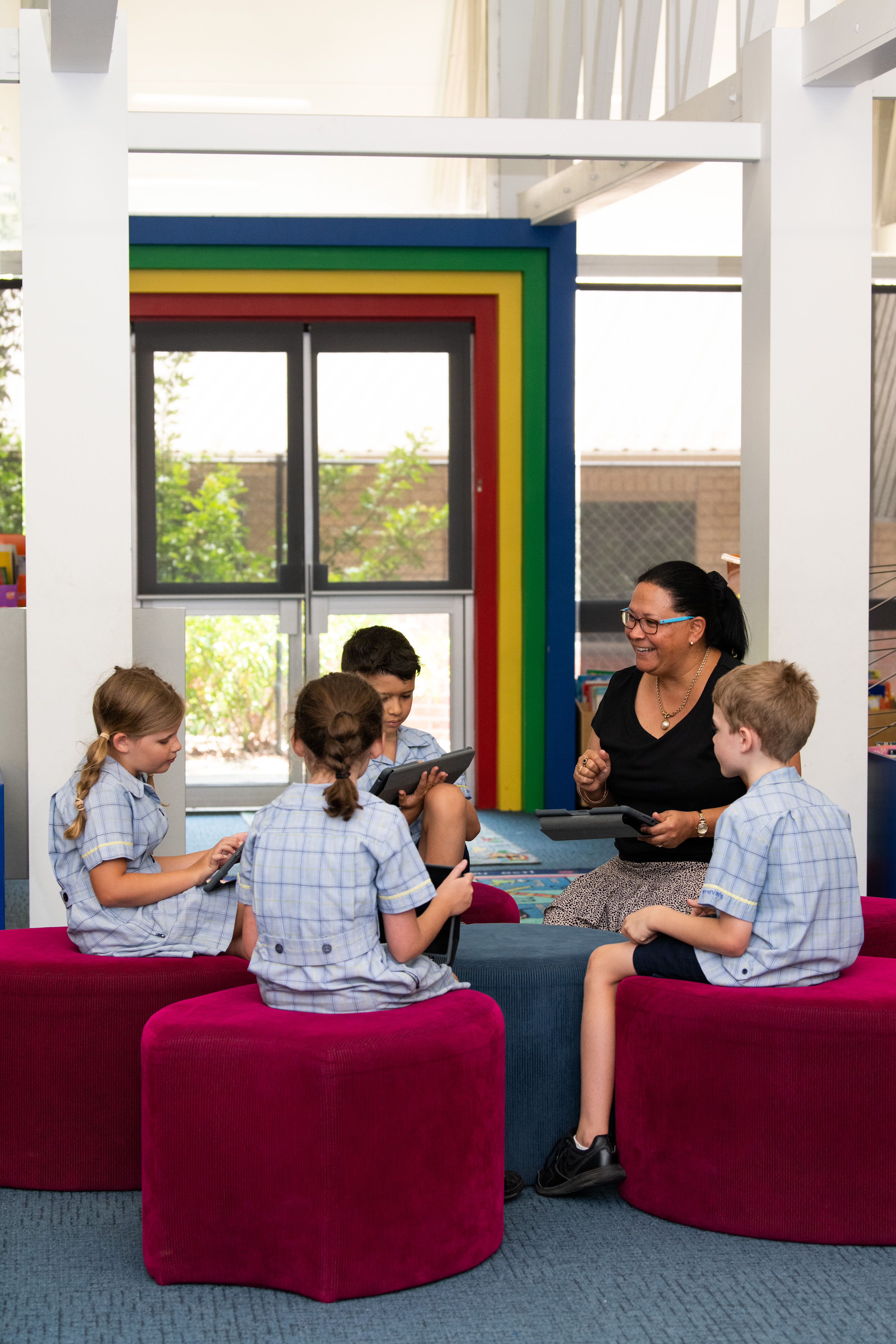 Four students sitting on red stools with a teacher. 